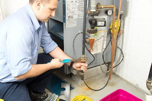 A furnace technician repairing and providing maintenance to a residential heating system in Brookline, MO. A furnace repair service by an HVAC expert.
