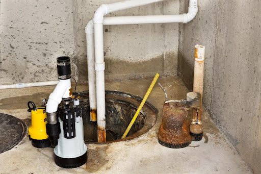 A sump pump being installed by a plumber in a residential basement in Fair Grove, MO with white pipes.