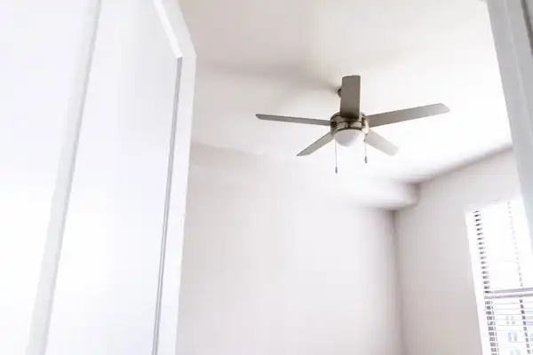 White ceiling fan in a bright room with white walls and a partially open door.