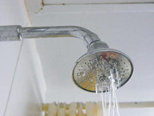 A shower head in a residential home in Springfield, MO that is experiencing low water pressure due to a drain clog in the plumbing system.