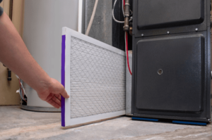 An HVAC technician changing a clean air filter on a high-efficiency furnace in a Springfield, MO home.