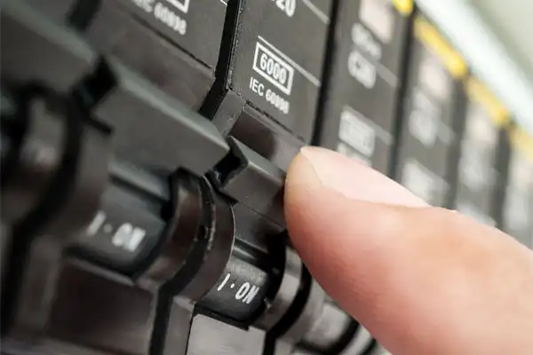 A finger switches on a circuit breaker labeled "6000/IEC 60998.