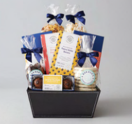 Gift basket with cookies, popcorn, and chocolate in a black container, adorned with blue ribbons and colorful packaging.